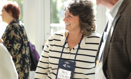 Attendee with a name badge laughing in conversation at the 2025 symposium